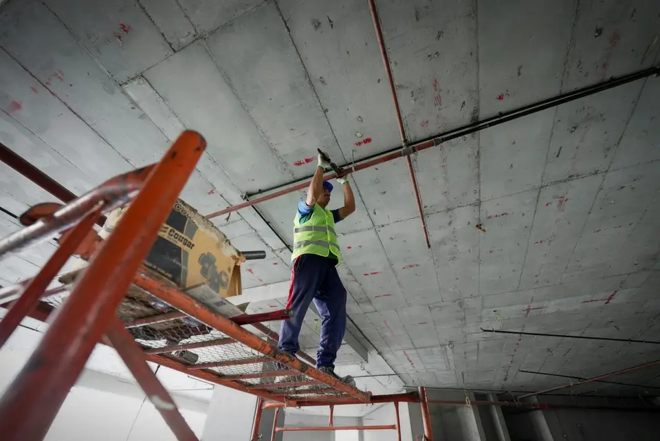 Crew hanging new drywall sheets on a basement ceiling with a drywall lift
