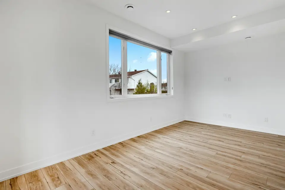 Installer fastening red oak hardwood strips over a plywood subfloor in a Massachusetts living room — Worcester, MA