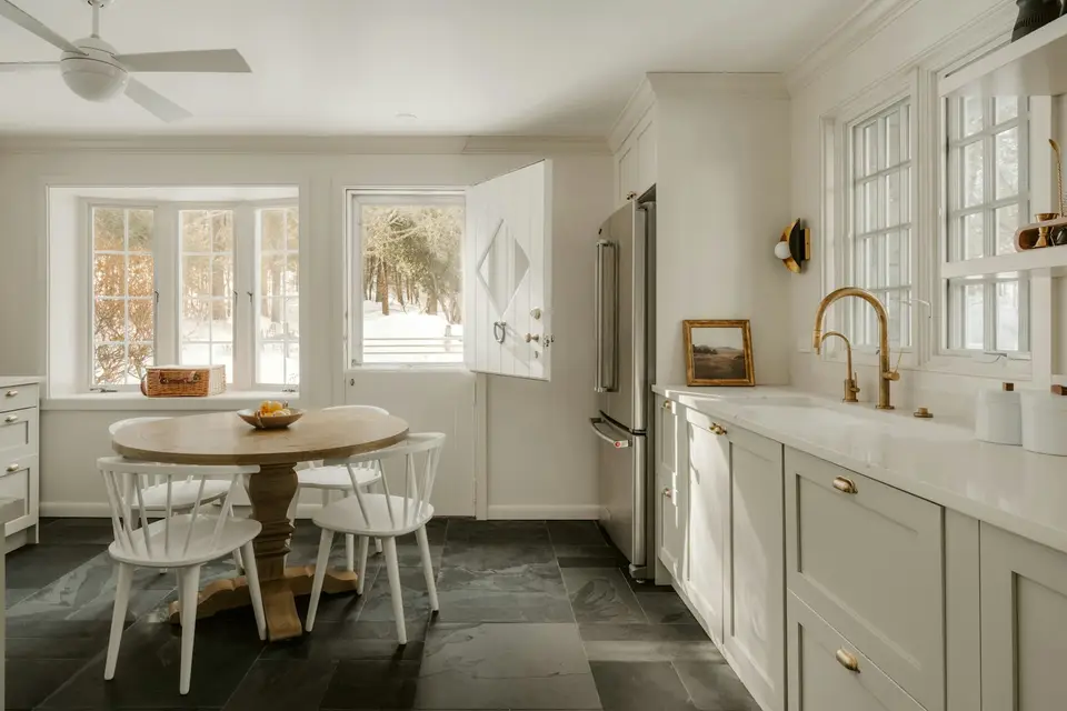 Renovated kitchen with white shaker cabinets, stone countertops and tile backsplash